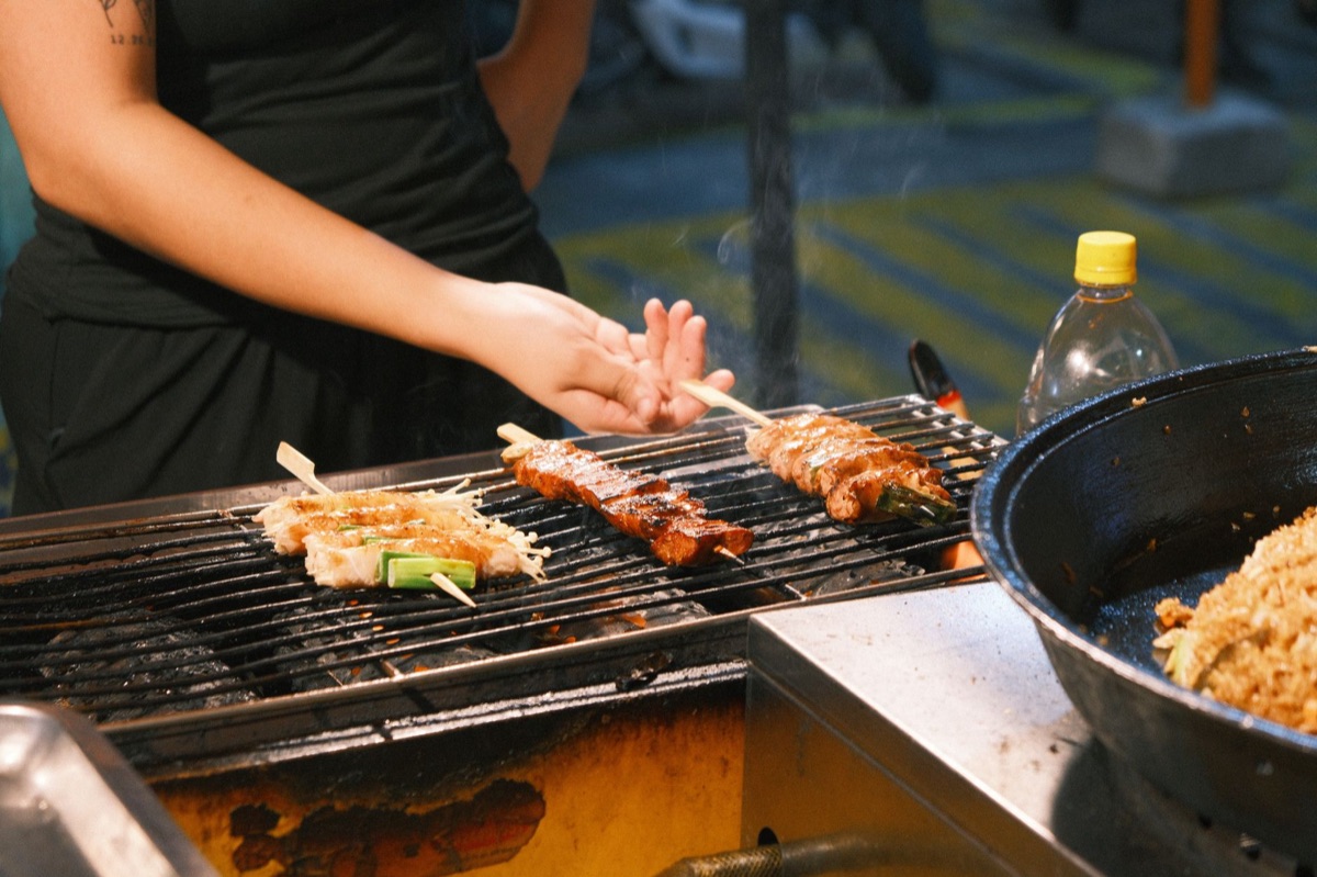 Korean street food vendor cart with skewers and grilled meats
