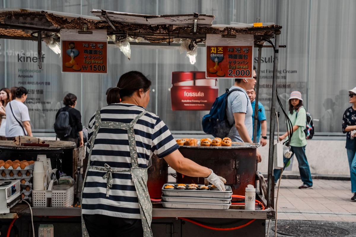 Un venditore coreano sta preparando bulgogi su un tavolo di vendita strada