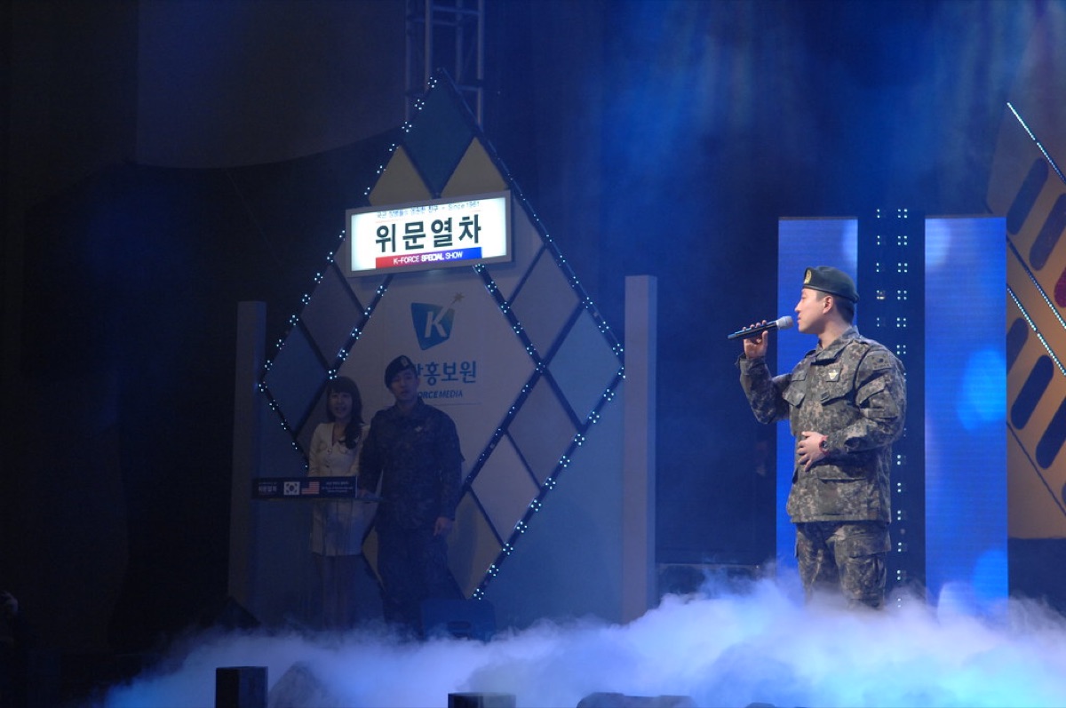 K-pop group performing on a stage with a large audience