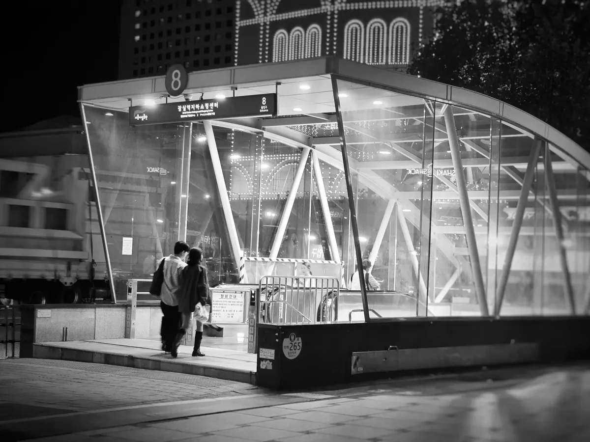 Black and white photo of people entering a subway in Seoul, South Korea at night.